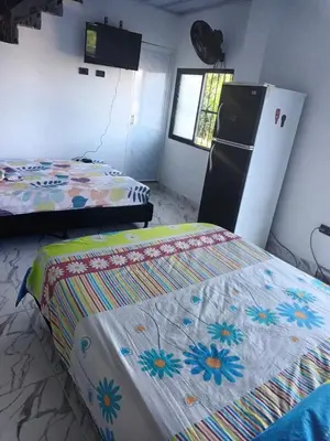 a room with two beds and a refrigerator in it at Casa Del Árbol in Doradal