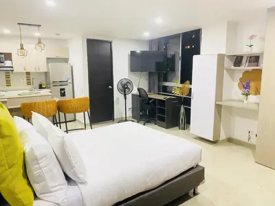 a bedroom with a white bed and a kitchen at 1009 Apartamento acogedor en el poblado Medellín in Medellín