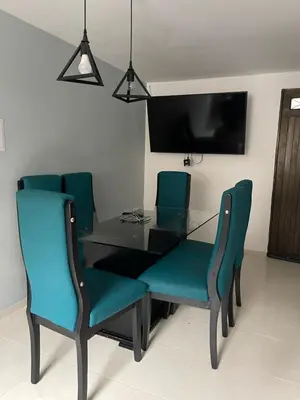 a dining room table with blue chairs and a television at Amplio apartamento en Niquia in Bello