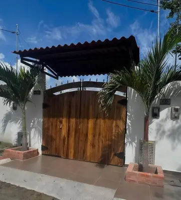 a wooden gate to a house with two palm trees at Apartamento Vacacional Campestre in Mariquita