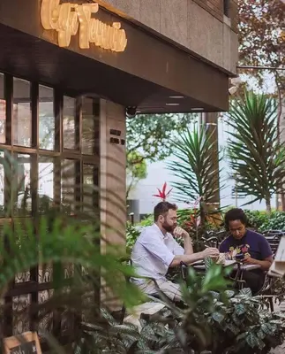two men sitting at a table outside of a building at Apartamento Lauret 2 en Laureles in Medellín