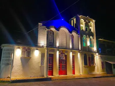 a white building with red doors at night at Apartamento Encanto in Puerto Triunfo