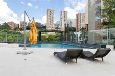 a pool with two chairs and an umbrella on a building at 501 Luxury Apartment In Heart Of El Poblado in Medellín