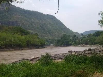 a river with rocks and trees and a mountain at Casa Rio y Montaña Low cost in Honda