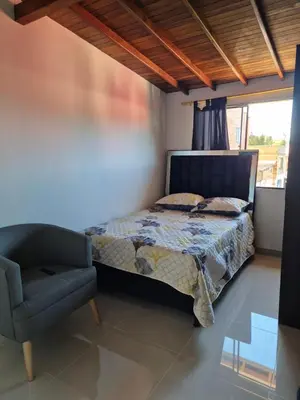 a bedroom with a bed and a chair and a window at EXCLUSIVO y ELEGANTE APARTAMENTO in Medellín
