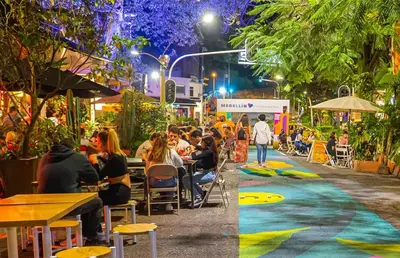 a group of people sitting at tables on a street at night at Habitación de Comfort total en el Poblado - A2 in Medellín