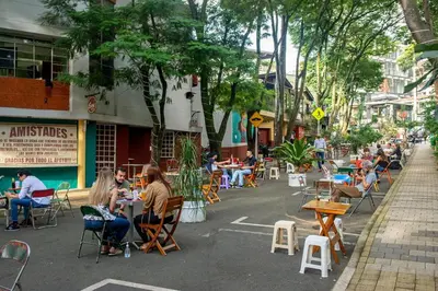a group of people sitting at tables on a street at Bello alojamiento baño compartido en el Poblado-A5 in Medellín