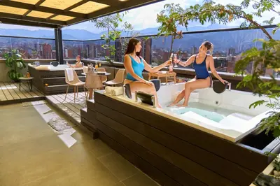 two women in bathing suits sitting in a bath tub on a building at Cozy Aparta-Suite Stadio Rosa Negra in Medellín