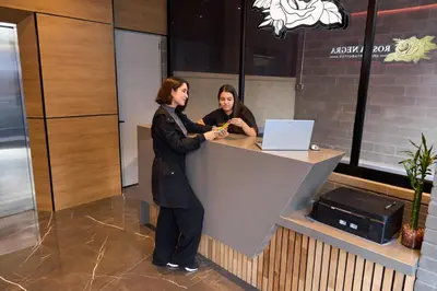 two women standing at a counter with a laptop at Comfy Aparta-Suite Stadio Rosa Negra in Medellín