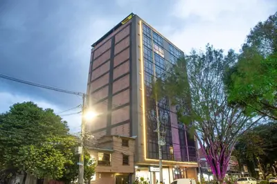 a tall building on a city street with trees at Cozy Aparta-Suite Stadio Jacuzzi Rosa Negra in Medellín