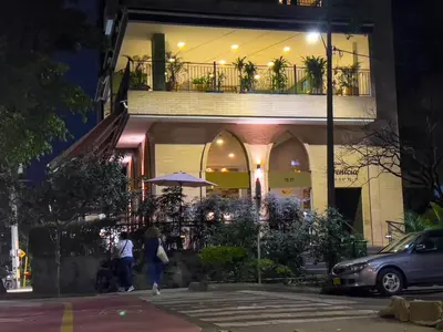 a building with people walking in front of it at night at Rosa Negra Haven Cozy Stadio Aparta-Suite in Medellín