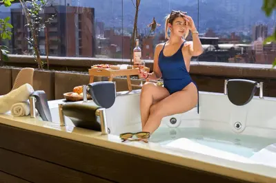 a woman in a bathing suit sitting in a bath tub at Elegant Cozy Suite Rosa Negra Stadio in Medellín