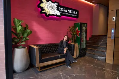 a woman sitting on a bench in front of a building at Comfortable Escape | Rosa Negra Stadio ApartaSuite in Medellín