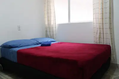 a bedroom with a bed with a red blanket and a window at Living Poblado Manila 3026 Habitación Individual in Medellín