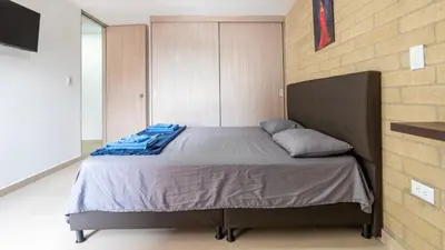a bed in a room with a brick wall at Apartamento 2BR Parqueadero y Piscina 202 in Medellín