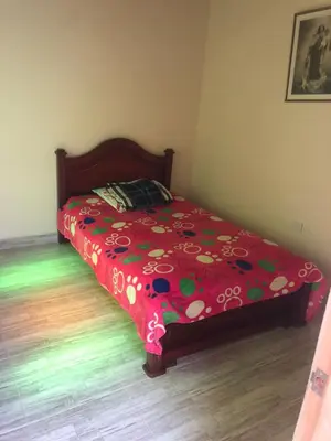 a bed with a red comforter with flowers on it at habitación amoblada en sonson antioquia colombia in Sonsón