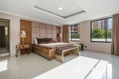 a bedroom with a bed and a table and windows at white house poblado in El Poblado