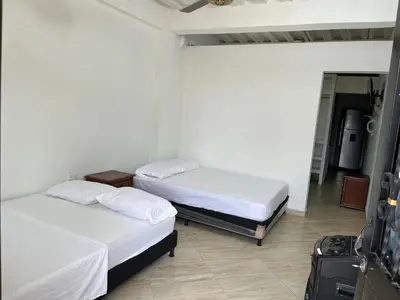 two beds in a room with a room with a suitcase at Apartamento Nápoles in Doradal