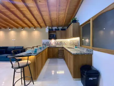 a kitchen with wooden cabinets and a counter with a bar at Casa Dorada - Confort a solo una cuadra del Parque in Carmen de Viboral