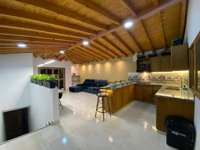 a large kitchen with wooden ceilings and a living room at Prosperity Room, Habitación doble - solo a una cuadra del parque in Carmen de Viboral
