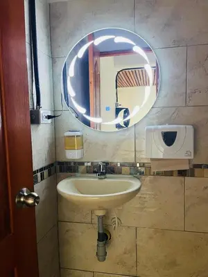 a bathroom with a sink and a round mirror at Hotel Curazao Natural Living in Cocorná
