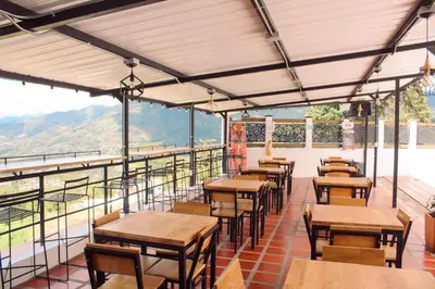 a restaurant with tables and chairs on a balcony at Curazao Natural Living in Cocorná