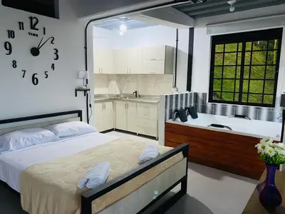 a bedroom with a bed and a bath tub and a clock at Hotel Curazao Natural Living in Cocorná