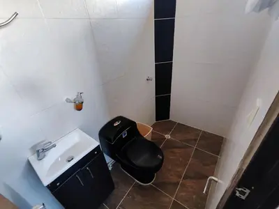 a bathroom with a black toilet and a sink at Augusto Hernandez in Santa Fe de Antioquia