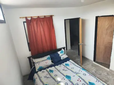 a bedroom with a bed with a red curtain and a door at Spacious and calm place to stay in Santa Fe de Antioquia