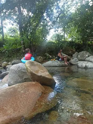 two people sitting on rocks next to a river at Cabin with River in San Rafael