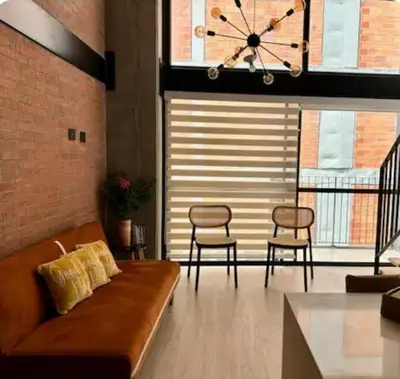 a living room with a couch and chairs and a clock at Hermoso Loft in Medellín