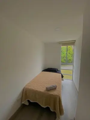 a bed in a white room with a window at Apartamento Urban Manizales in Manizales
