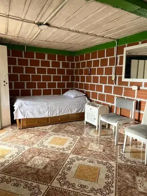 a bedroom with a brick wall with a bed and two chairs at Coffee Tour, Colombia Aranzazu Caldas- Andean Motmot coffee in Aranzazu