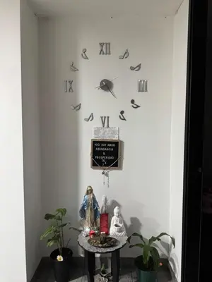 a clock on a wall with a table and plants at Apartamento alto de palmas in Medellín
