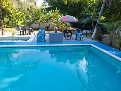 a swimming pool with chairs and a table and an umbrella at cabaña in Honda