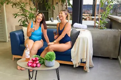 two women in bathing suits sitting on a couch at Cozy Comforts at Rosa Negra Stadio in Medellín