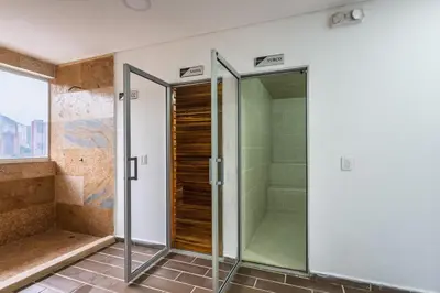 a glass shower with a glass door in a bathroom at Apartasuite Sabaneta City view parking in Sabaneta