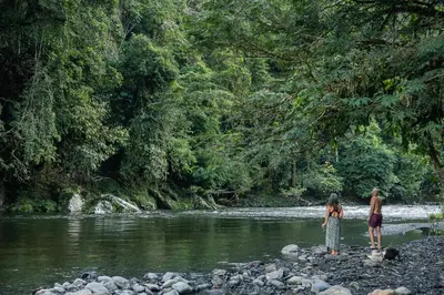 two people standing on rocks near a river at Casa Borojó, Refugio Natural Jacaranda in Cocorná