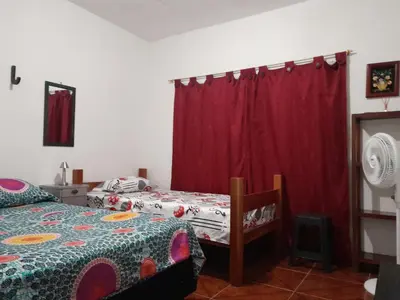 a bedroom with two beds and a red curtain at Casa de pesca in Honda