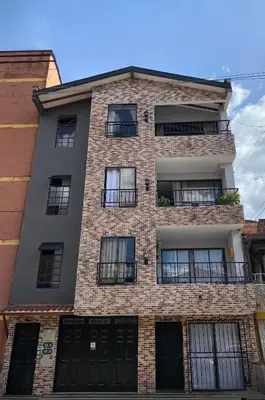 a tall brick building with black doors and windows at Apartamento cerca al metro y viva envigado in Itagüí