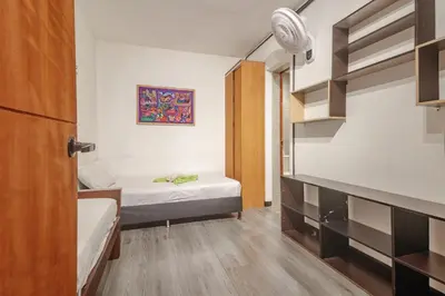 a small room with two beds and a closet at Hostal Machu Picchu Medellin in Estación El Salto
