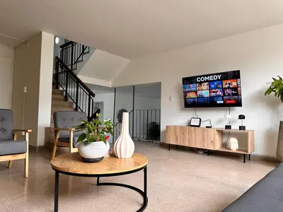 a living room with a table and a tv on the wall at Exclusive Group Accomodation in Medellín