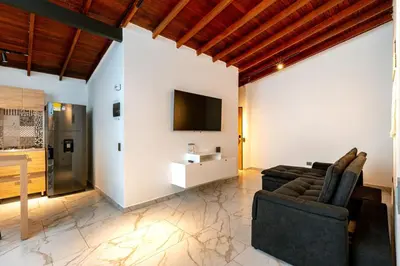 a living room with a couch and a tv on a wall at L3 9BR Laureles House Rooftop 2 Jacuzzis AC in Medellín