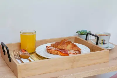 a wooden tray with a sandwich and a glass of orange juice at Large Apt-Laureles-Smart Lock-AC-Laundry Service in Medellín