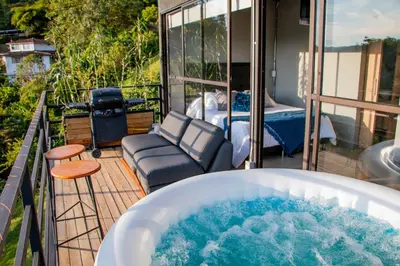 a jacuzzi tub on a balcony with a bed at Roots Eco House in Guatapé