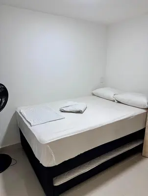a bed with white sheets and towels on it at Apartamento laureles estadio 201 ED MILA in Medellín