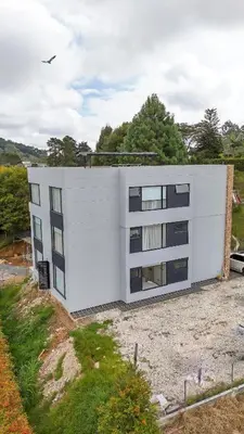 a white building sitting on top of a field at Apartamento de lujo a 3 minutos del Aeropuerto JMC 101 in Rionegro