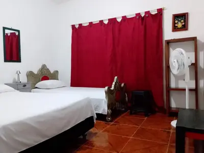 a bedroom with a bed and a red curtain at Brisas del Río in Honda