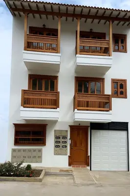 a white building with wooden balconies and a garage at Las Flores de Mria 303 in Jardin
