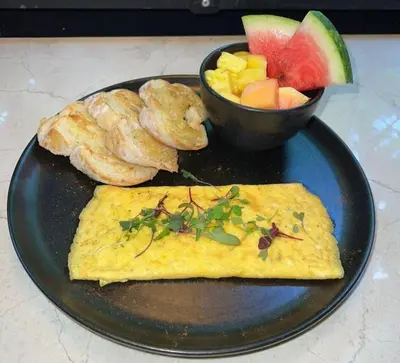 a black plate with an omelet and a bowl of fruit at Hotel Ryo 74b Piso 7 Vip in Medellín